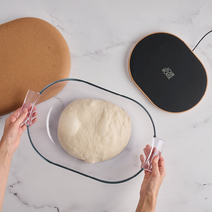 Product photo of DoughBed glass bowl for bread dough proofing and warming mat on white quartz countertop background