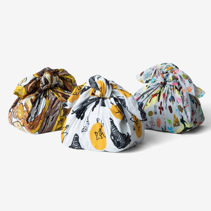 Three Bread Blankets warpped around loaves of bread with colorful patterns on a white background