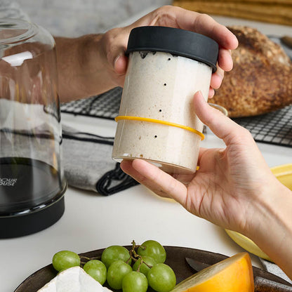 Hand holding Sourhouse glass sourdough starter jar with silicone lid and active starter inside